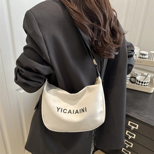Minimalist canvas hobo bag with letter print shown on a model wearing a black blazer