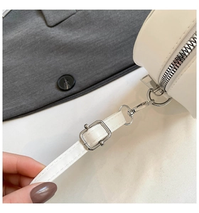 Détail d'un sac bandoulière en cuir blanc avec fermeture éclair et boucles métalliques