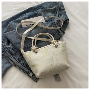 Détail du sac cabas crème avec motif bambou bleu et pompon décoratif gris sur le côté