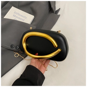 Close-up of a black evening bag with a large golden metal handle and chain strap