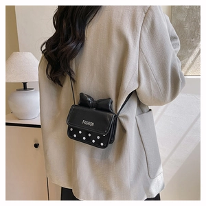 Rear view of a model wearing the cute black polka dot mini crossbody bag with a bow