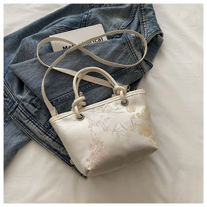 Détail de broderie chinoise sur sac seau crème avec poignées à nœuds élégantes