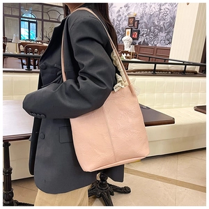 Close-up of pink tote bag with textured floral embossing worn by a model in a cafe