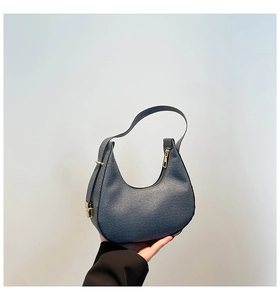 Detailed view of dark blue denim hobo bag texture with golden metallic hardware