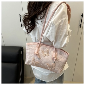 Detail of pink lace tote bag featuring 3D butterfly embroidery and slim leather handles