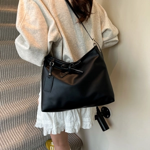 Minimalistische schwarze Shopper-Tasche aus Leder mit Schleife am Modell getragen