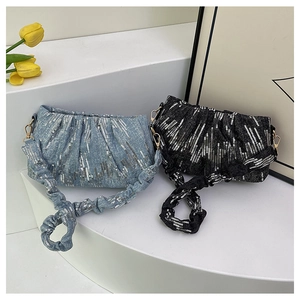 Detail of sequined cloud bags in blue and black with ruched straps on white stand