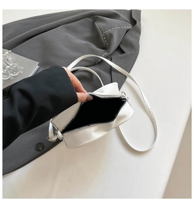 Vue détaillée du sac bandoulière en cuir blanc avec fermeture éclair argentée et doublure noire