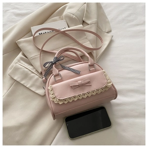 Detailed view of pink bow handbag featuring white lace edges and a checkered ribbon