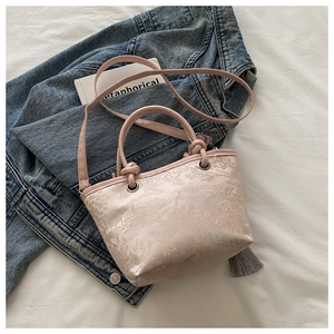 Détail d'un sac seau rose en jacquard avec broderie florale et pompon décoratif élégant