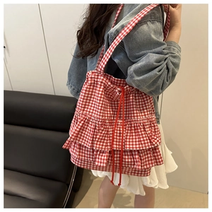 Detail of red and white checkered tote bag featuring layered ruffles and drawstring closure