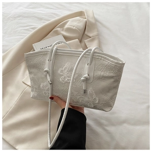 Close-up of elegant white floral butterfly lace embroidery texture on a stylish handbag