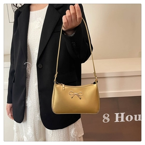 Detailed view of a gold hobo bag featuring a metallic bow accent and matte leather finish
