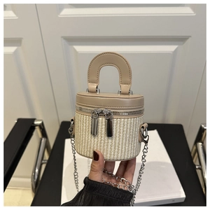 Detail of mini straw bucket bag with khaki leather trim and silver chain shoulder strap
