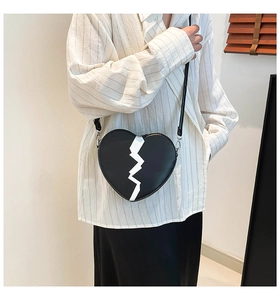 Détail du sac à bandoulière en forme de cœur avec motif craquelé blanc sur similicuir noir