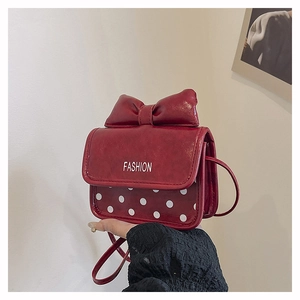 Detail of red bowknot crossbody bag with polka dot pattern and fashion lettering