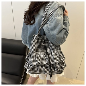 Detail of checkered canvas tote bag featuring triple-layered ruffles and drawstring closure
