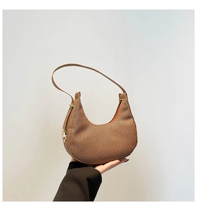 Detail of a brown moon hobo bag with textured leather and contrast orange lining