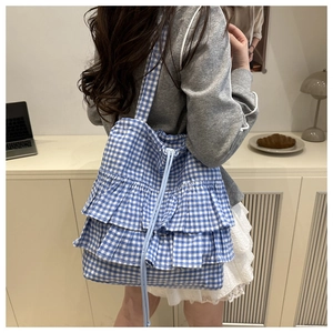 Close-up of blue gingham canvas tote bag with ruffled layers and drawstring closure