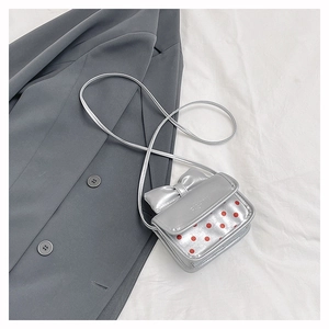 Close-up of silver mini bag featuring a bow detail and red polka dot pattern texture