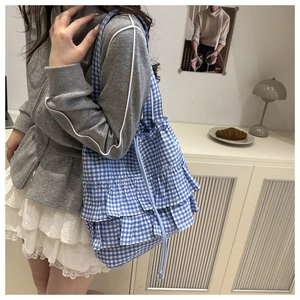 Detail view of blue gingham tote bag with layered ruffle trim and drawstring handle
