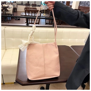 Close-up of pink pleated leather tote bag featuring a decorative white lace bow charm