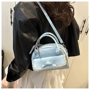 Detail of light blue handbag with bow and lace edge shown with model styling