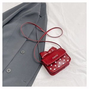Detail of red bow crossbody bag with white polka dots and FASHION lettering