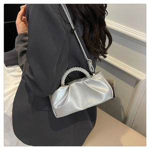Close-up of silver pleated bag with elegant pearl handle and metallic finish