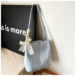Close-up of light blue shoulder bag with pleated texture and a delicate lace bow detail