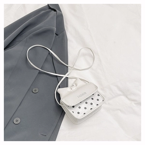 Detail of white mini crossbody bag with fashion lettering and chic bow decoration