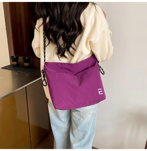 Detail of purple nylon crossbody bag with polka dot strap and logo on front pocket
