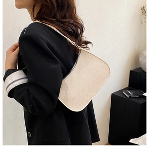 Detail of minimalist cream leather underarm bag with lychee texture and crescent design