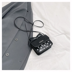 Detail of black bow shoulder bag with white polka dots and FASHION lettering
