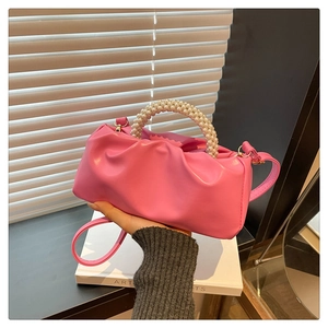 Detail of pink pleated mini bag with pearl beaded handle and glossy leather finish