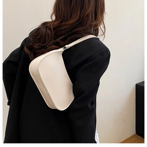 Detailed texture of white lychee grain leather on a stylish minimalist hobo shoulder bag