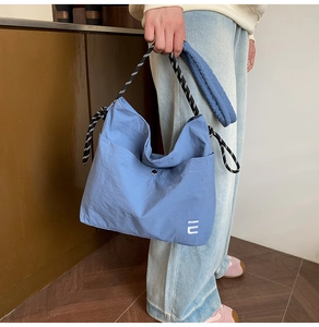 Détail du sac à bandoulière en nylon bleu avec bandoulière corde noir et blanc et logo E