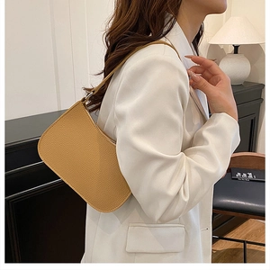 Brown litchi grain shoulder bag worn with a white blazer for a stylish urban look