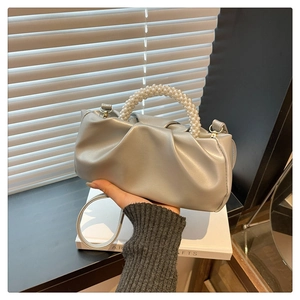 Detail of silver pleated cloud bag with elegant large pearl handle and soft leather texture