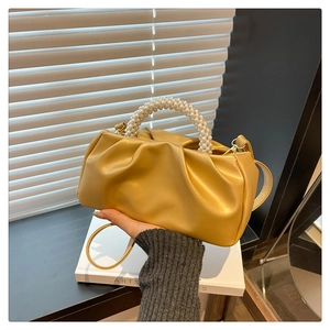 Detail of golden pleated cloud bag featuring premium pearl bead handle and PU leather texture