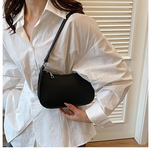 Fashionable black pebbled leather hobo bag worn on shoulder by model in neutral setting