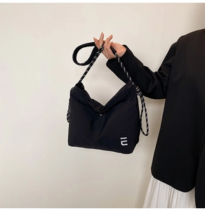 Detail of nylon hobo bag featuring black and white woven rope strap and logo embroidery