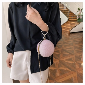 Detailed close-up of pink glitter sphere evening bag with round metal handle and chain