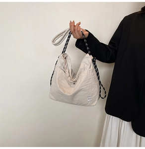 Detail of beige nylon tote bag with drawstring, rope strap and purple embroidery