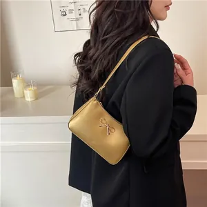 Chic gold bow shoulder bag with metallic finish shown on model in cozy room setting