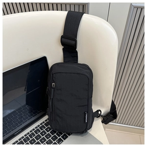 Detail of minimalist black nylon chest bag with adjustable strap and front zipper pocket