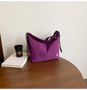 Détail du sac bandoulière en nylon violet avec bandoulière en corde sur table en bois