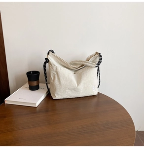 Détail du sac bandoulière en nylon beige avec bandoulière corde sur table en bois