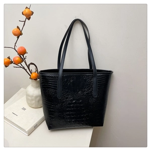 Detail view of black crocodile pattern leather tote bag with elegant handles