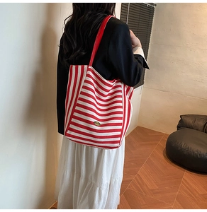 Detail of a large red and white striped canvas tote bag with slim shoulder straps